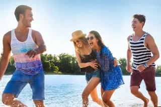 Vier fröhliche Personen am Wasser.