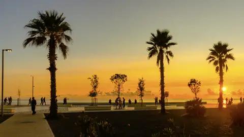 Bei unserer Rundreise genießen wir einen atemberaubenden Sonnenuntergang an der palmengesäumten Promenade von Durres an der Adriaküste.